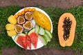 Assortment of sliced tropical fruits on on a background of green grass. Royalty Free Stock Photo