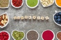 Assortment of superfoods on a gray background. matcha, acai, turmeric, fruits, berries, nuts and seeds. vegan food.