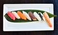 Assortment sushi on a white plate over the black table