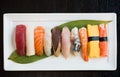 Assortment sushi on a white plate over the black table
