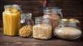 Assortment of uncooked grains, cereals and pasta in glass jars on wooden table