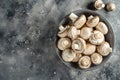 Assortment of white mushrooms in a bowl on a speckled grey background with room for text