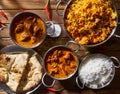 Assortmnent of indian dishes including, butter chicken, lamb tikka masala, biryani with naan and raita