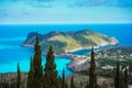 Assos village and coastline of beautiful blue sea. Cypress trees in foreground. Kefalonia island, Greece