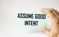 Assume good intent, card is held by female hand on white background. Good intentions on sticker, positive