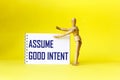 Assume Good Intent, inspirational quote on notepad with wooden doll, positivity concept