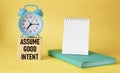 Assume good intentions. Inspirational quote with notepad to write on yellow background with alarm clock.