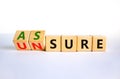 Assure or unsure symbol. Turned wooden cubes and changed the concept word unsure to assure. Beautiful white table, white