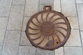 ÃÂ¡ast iron manhole cover is located on the pavement of gray concrete tiles