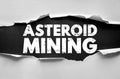 ASTEROID MINING text seen through torn paper. Conceptual visual representing space industry, resource extraction, futuristic Royalty Free Stock Photo