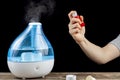 A woman holding an inhaler to administer bronchodilator or steroid puff to herself.