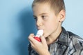 Asthma boy with is inhalator over blue background Royalty Free Stock Photo