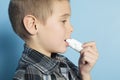 Asthma boy with is inhalator over blue background Royalty Free Stock Photo
