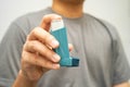 Asthma and chronic obstructive pulmonary disease COPD, Asian young man using metered dose inhaler MDI Royalty Free Stock Photo