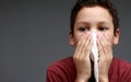 asthmatic breathing problems catching the flu child blowing nose after having a cold on grey background with people stock photo Royalty Free Stock Photo