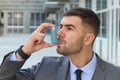 Asthmatic businessman using an inhaler at work Royalty Free Stock Photo