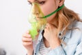 Asthmatic woman holding green respiratory mask