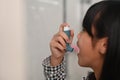 Asthmatic young girl using an asthma inhaler while suffering from asthma in toilet.