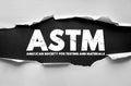 ASTM American Society for Testing and Materials text on torn paper background symbolizing quality standards and certification Royalty Free Stock Photo