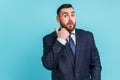 Astonished bearded man wearing dark suit pointing finger aside, showing copy space for commercial Royalty Free Stock Photo