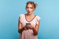 Astonished beautiful young adult woman in summer dress, using smartphone and watching shocking video, reading message with amazed Royalty Free Stock Photo