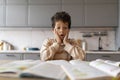 Astonished black boy looking shocked while studying with textbooks at home Royalty Free Stock Photo