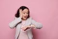 Astonished businesswoman checking time on her wristwatch, being late for business meeting, isolated on pink background Royalty Free Stock Photo