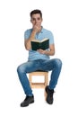 Astonished casual man covering his mouth and holding a book Royalty Free Stock Photo