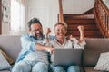 Astonished caucasian couple celebrating online success using laptop sitting on sofa at home. Joyful wife and husband surprised by Royalty Free Stock Photo