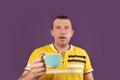 Astonished man with a cup, on a purple background