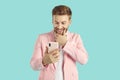Astonished stylish young man holding smartphone and looking at it Royalty Free Stock Photo