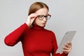 Astonished and surprised stylish business woman in red turtleneck using tablet computer, reads something important about finance Royalty Free Stock Photo