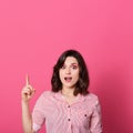 Astonished woman with good idea, pointing her finger up at copy space isolated over pink background, lady dresses casual attire, Royalty Free Stock Photo
