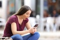 Astonished woman with a phone in the street