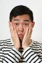 Astonished young Asian man covering his face with palms Royalty Free Stock Photo