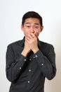 Astonished young Asian man covering his mouth with hands