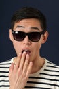 Astonished young Asian man in sunglasses covering his mouth by p Royalty Free Stock Photo