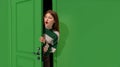 Astonished young girl, teengager peeking out green door with shocked face, looking with wide open eyes. Surprise Royalty Free Stock Photo