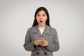 Shocked woman holding phone, surprised by unexpected news Royalty Free Stock Photo