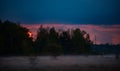 Astonishing sunset over the forest after a stormy day. Foggy evening over the meadow creating a unique picturesque landscape Royalty Free Stock Photo