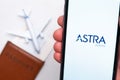 Astra Airline app on a smartphone screen with a plane and passport on the background. The concept of travel app