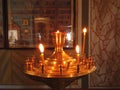 Astrakhan Russia - 10 October 2020: Candles burning on golden stand in front of the saints pictures on the wall Royalty Free Stock Photo