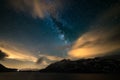 Astro night sky, Milky way galaxy stars over the Alps, stormy sky, motion clouds, snowcapped mountain range and lake Royalty Free Stock Photo