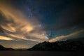 Astro night sky, Milky way galaxy stars over the Alps, stormy sky, motion clouds, snowcapped mountain range and lake Royalty Free Stock Photo