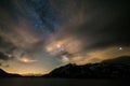 Astro night sky, Milky way galaxy stars over the Alps, stormy sky, motion clouds, snowcapped mountain range and lake Royalty Free Stock Photo