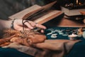 Astrology and esotericism. The female hand of the sorceress holds an amulet in her hands. In the background, old books, fortune-