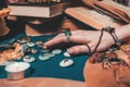 Astrology and esotericism. The female hand of the sorceress reads the runes. In the background, old books, fortune-telling runes,