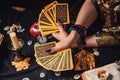 Astrology and esotericism. A fortune teller holds a fan of Tarot cards. On the table are runes and magic glass pyramid. Close-up Royalty Free Stock Photo