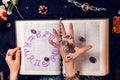 Astrology and horoscope. The fortune teller& x27;s hand holds the zodiac stones in the palm of her hand over the open book