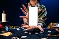 Astrology. Witch`s hands hold a cellphone with a white screen. Mock up. The concept of divination and predictions with the help o
